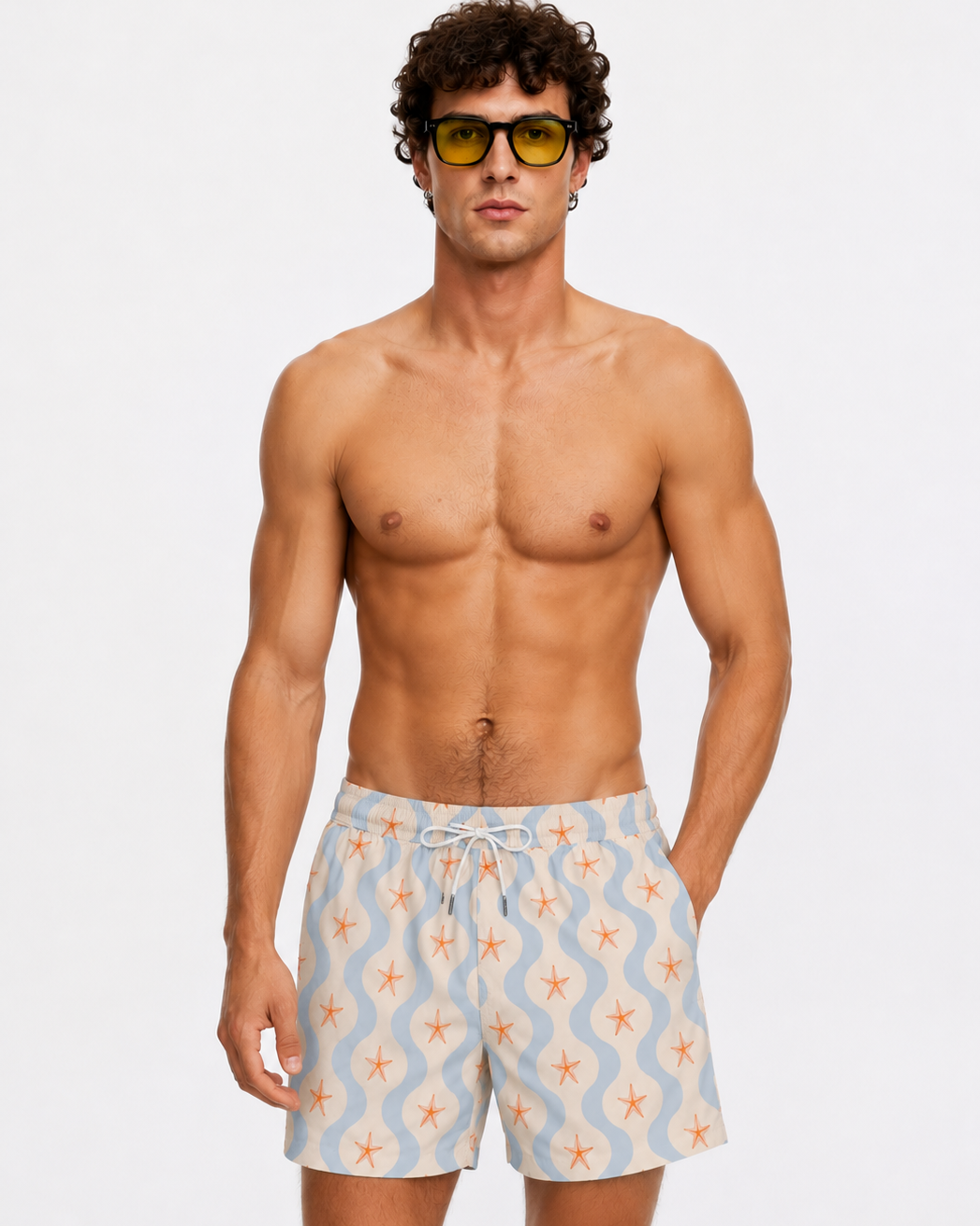 Man wearing patterned swim shorts and sunglasses on a plain background