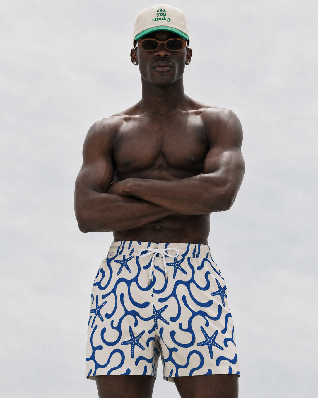 Man wearing a cap and patterned shorts against a plain background