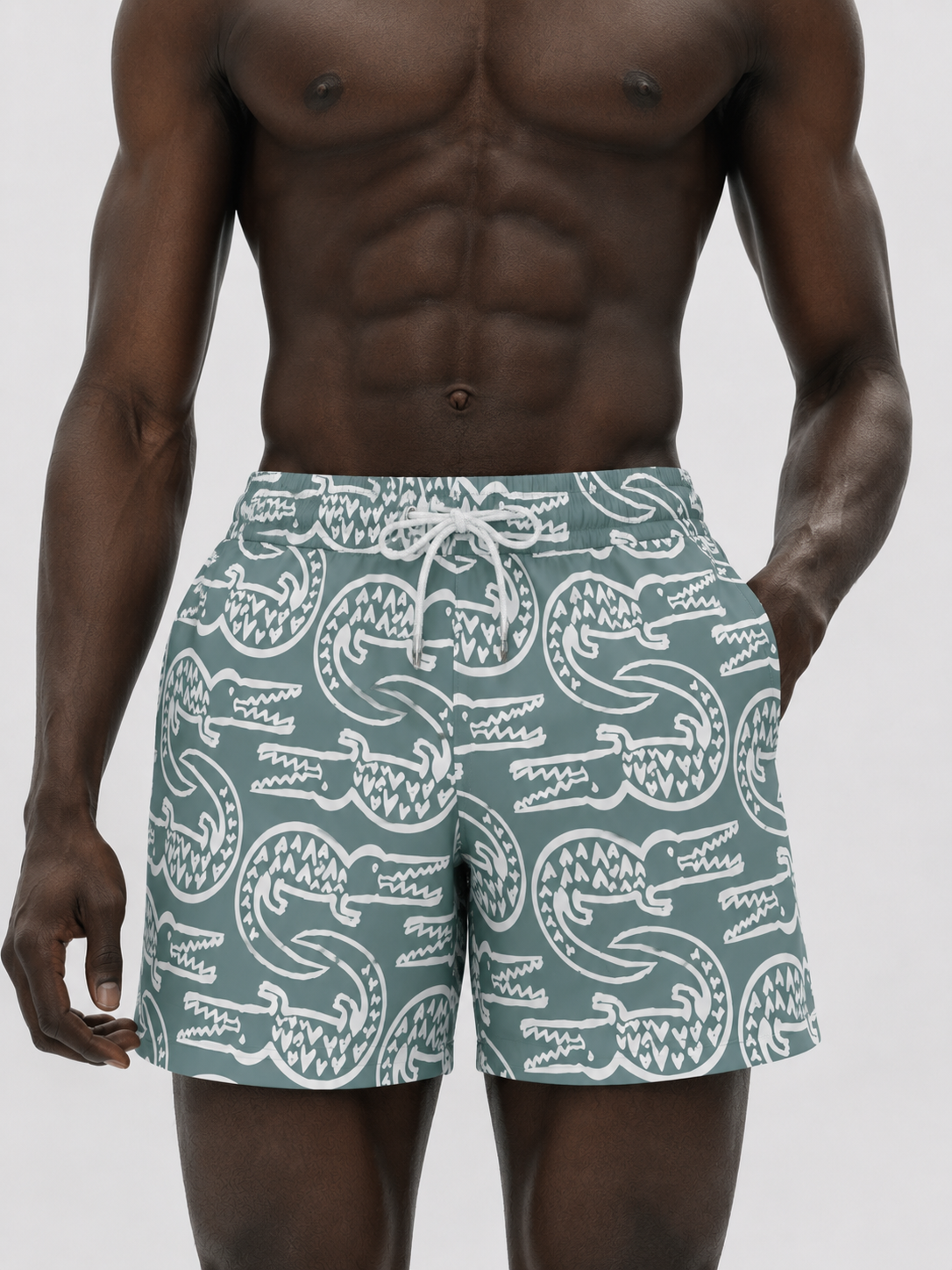 Man wearing green swim shorts with white crocodile pattern on a plain background