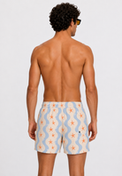 Man wearing patterned swim shorts on a plain background