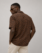 Man wearing a leopard print shirt and sunglasses on a plain background