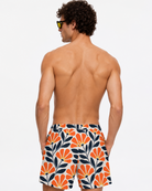 Man wearing a colorful floral-patterned swimsuit on a white background