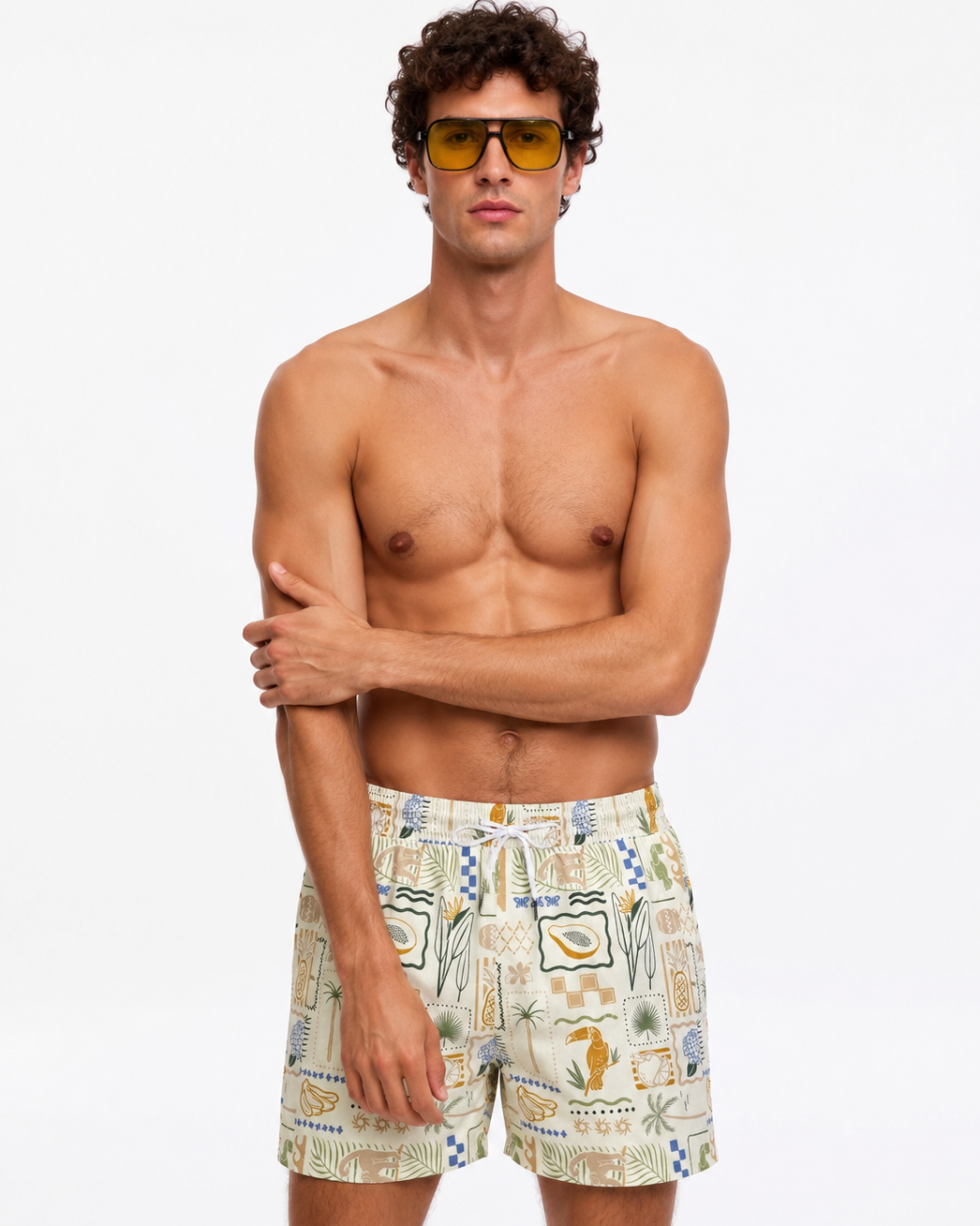 Man wearing patterned swim shorts and sunglasses on a white background