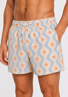 Beige swim shorts with starfish pattern on a plain background