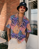 Man wearing a colorful shirt and black bucket hat standing in front of a building.