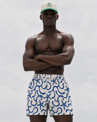 Man wearing a cap and patterned shorts against a plain background