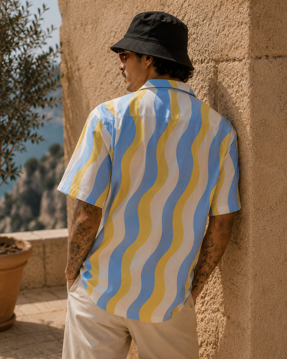 Person wearing a colorful shirt leaning against a stone wall with a scenic background.