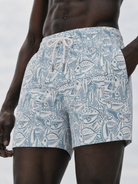 Person wearing blue patterned swim shorts on a plain background