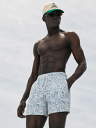 Man wearing light blue patterned swim shorts against a white background