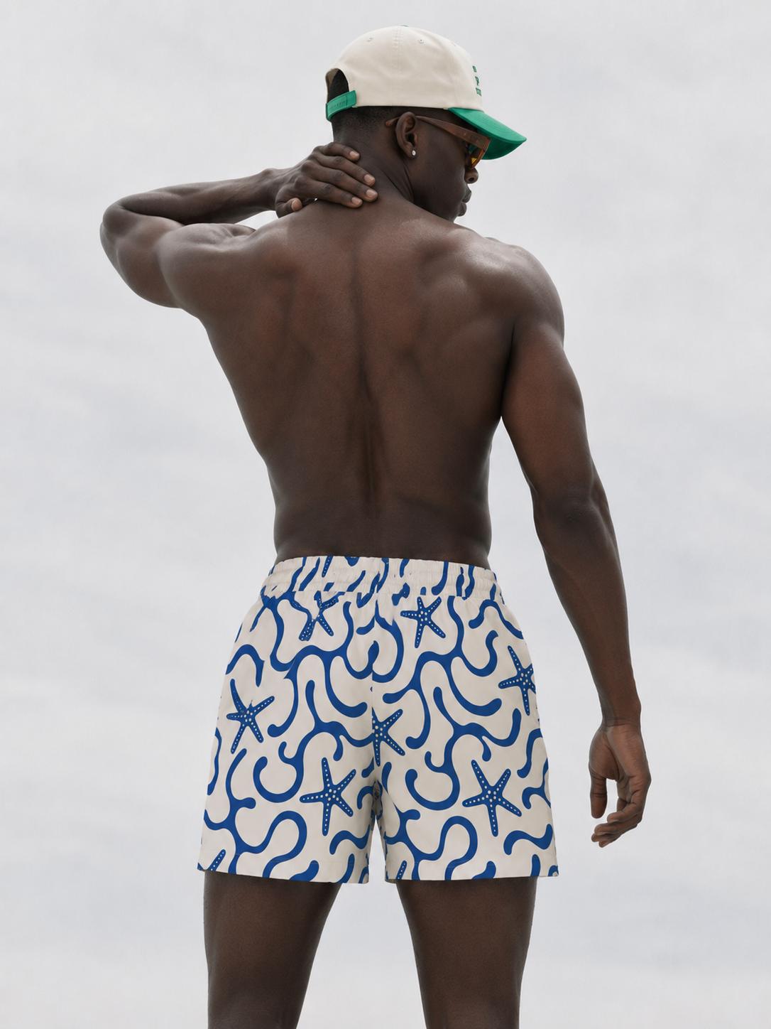 Man wearing blue and white patterned swim shorts on a plain background